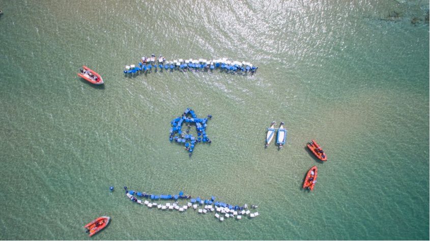 גולשים יוצרים את דגל ישראל בחוף אורנים באשדוד. צילום רחפן: שבתאי טל
