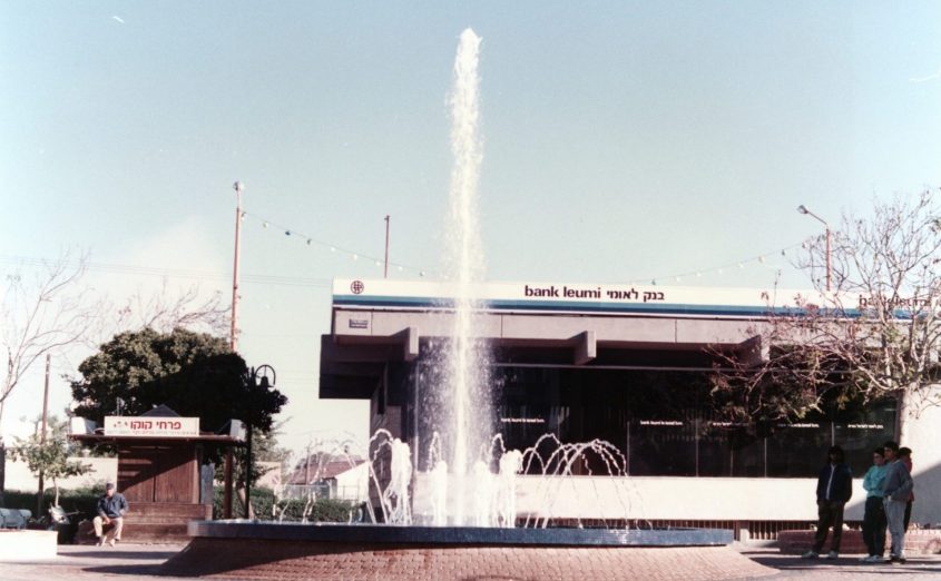 המזרקה על רקע בנק לאומי, מרכז מסחרי רובע א', אשדוד, 1987. באדיבות הארכיון העירוני אשדוד
