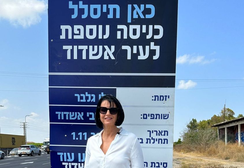 הלן גלבר ליד השלט שתלתה בצומת אמונים. צילום: עדן בוהדנה